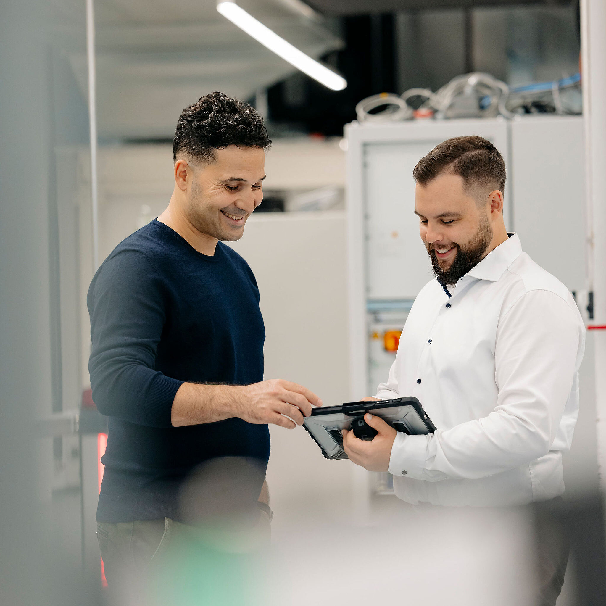 Two Silver Atena employees discussing technical test results displayed on a tablet in the laboratory.