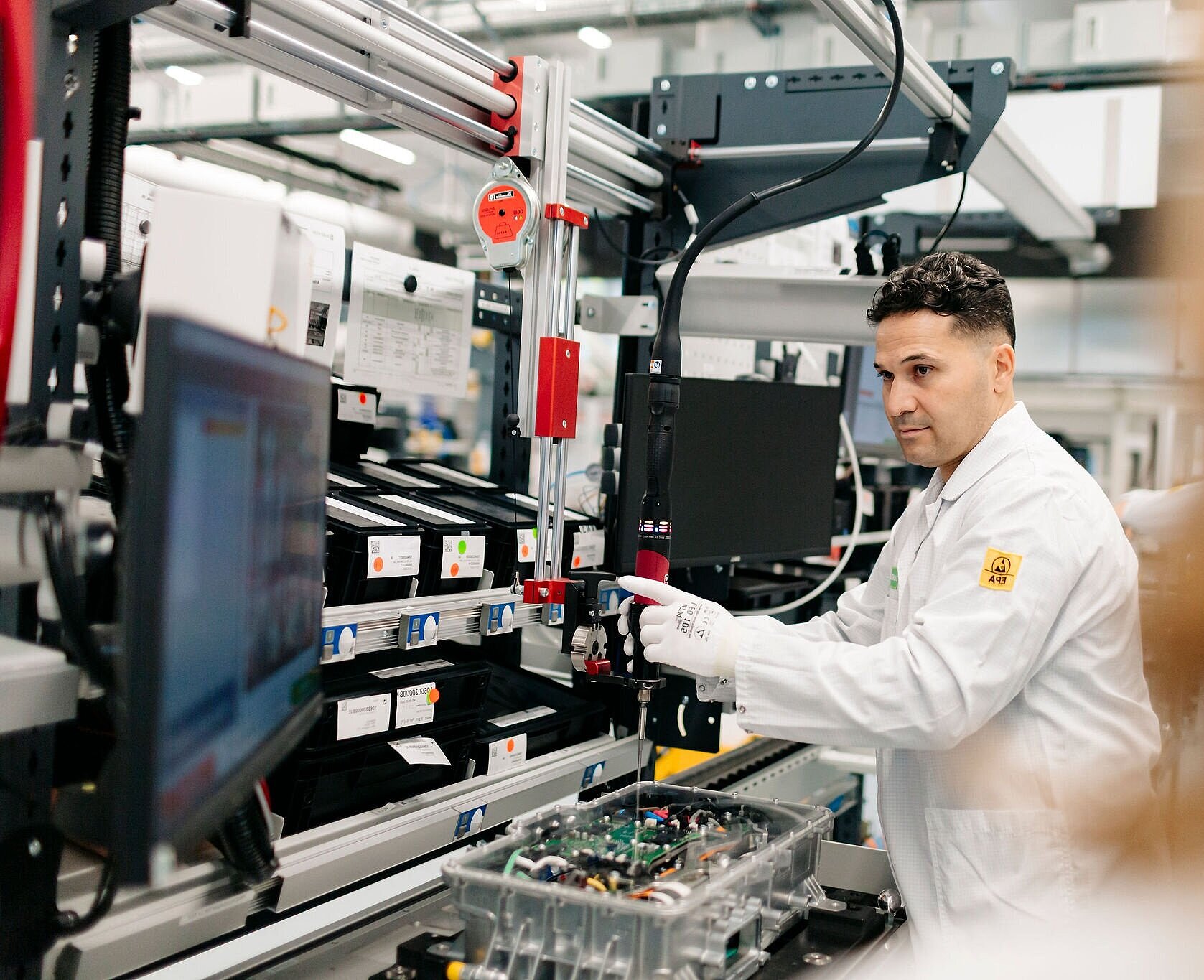 Person at a production station with electronic unit and guided tool system.