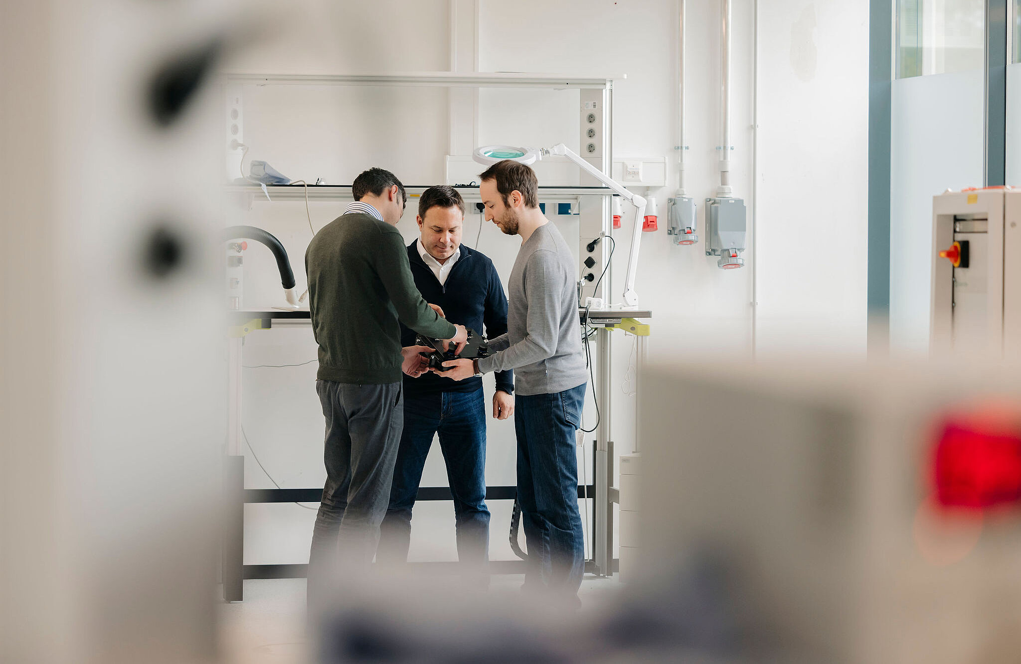 Three Silver Atena engineers discussing a technical assembly in the development laboratory.