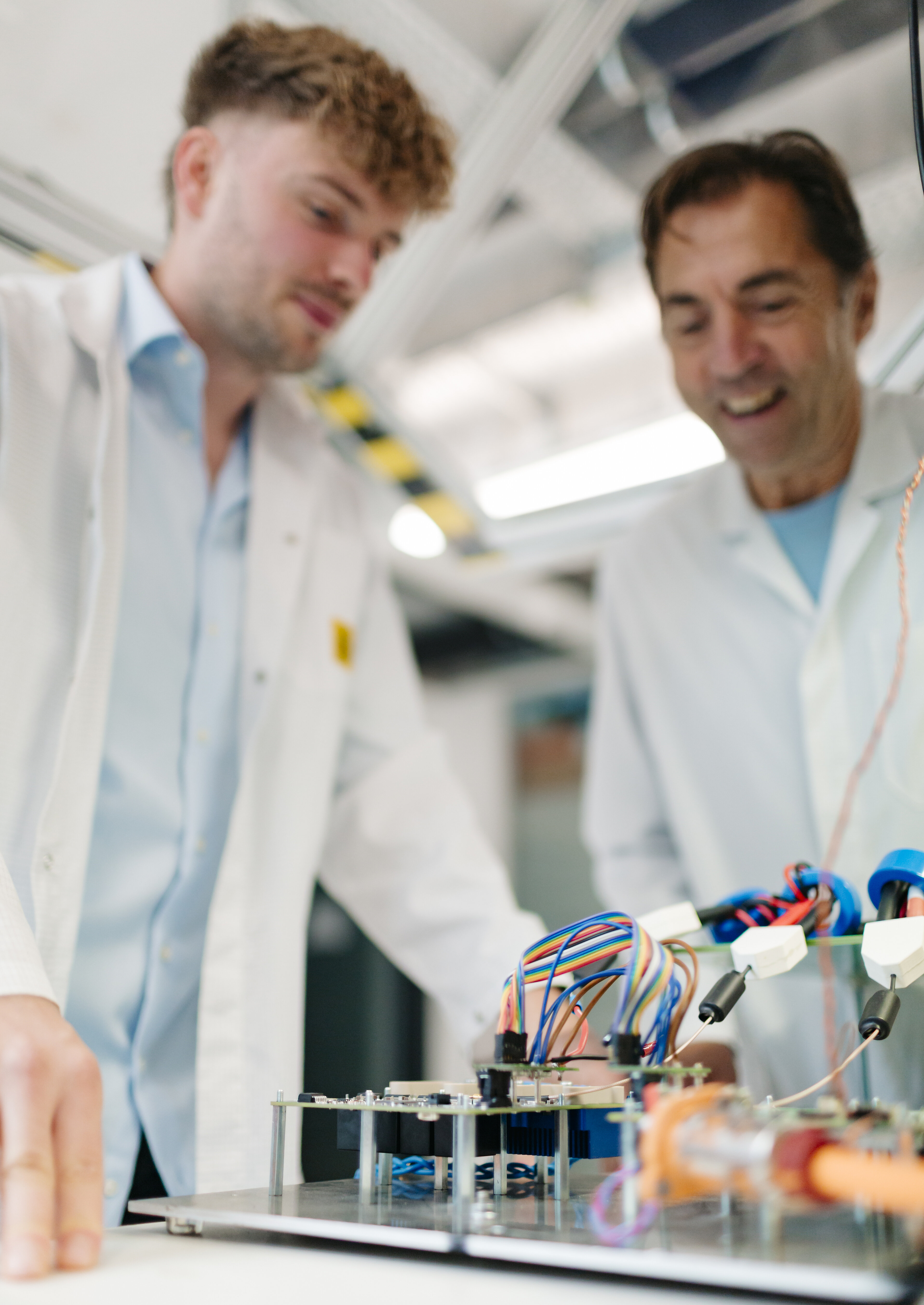 Two people in a lab working on an electronic unit with wiring.