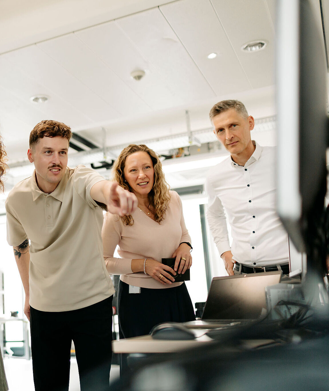 Five Silver Atena employees discussing technical results together at a computer workstation in the development laboratory.