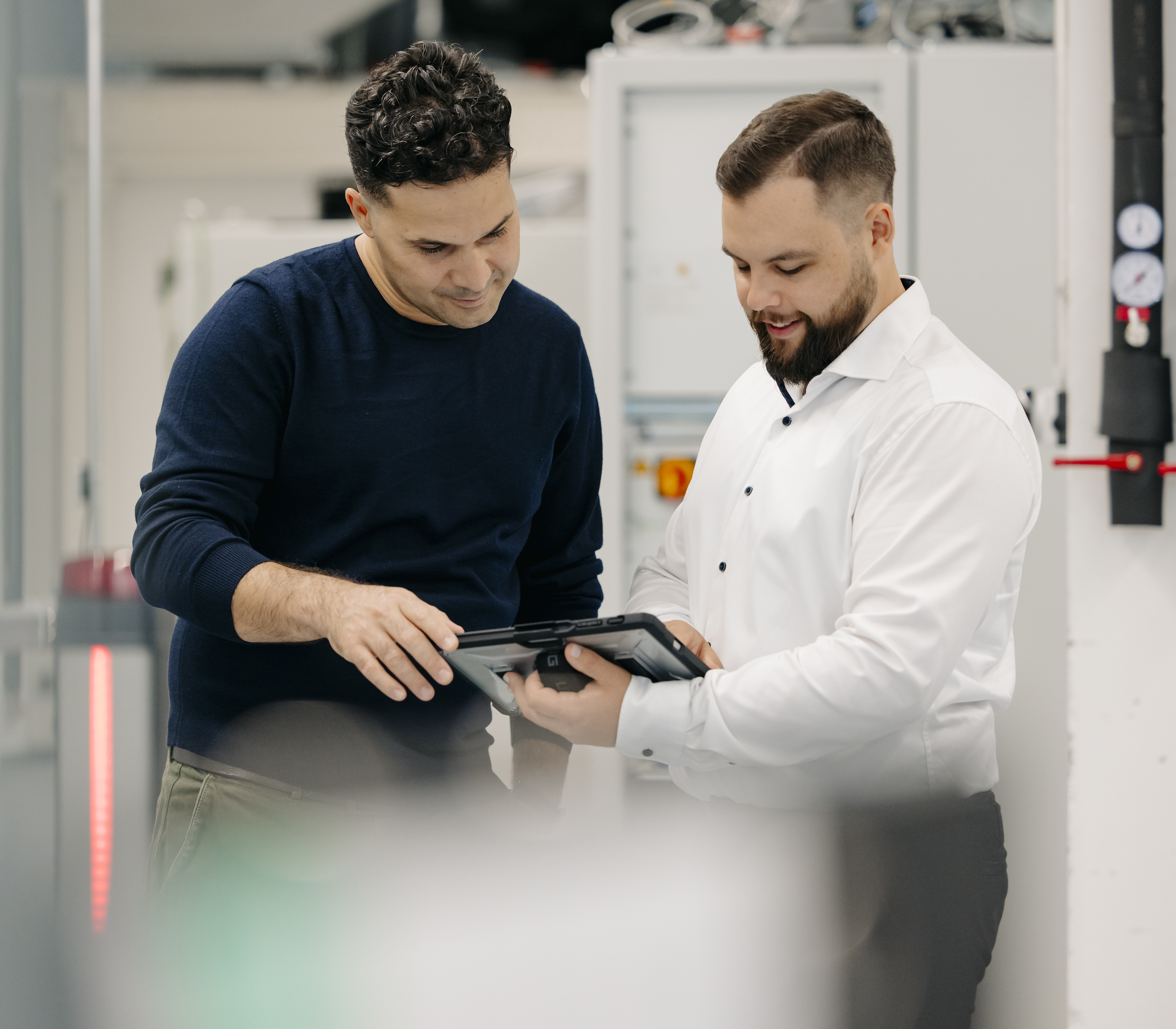 Two people in a production environment reviewing data on a tablet.