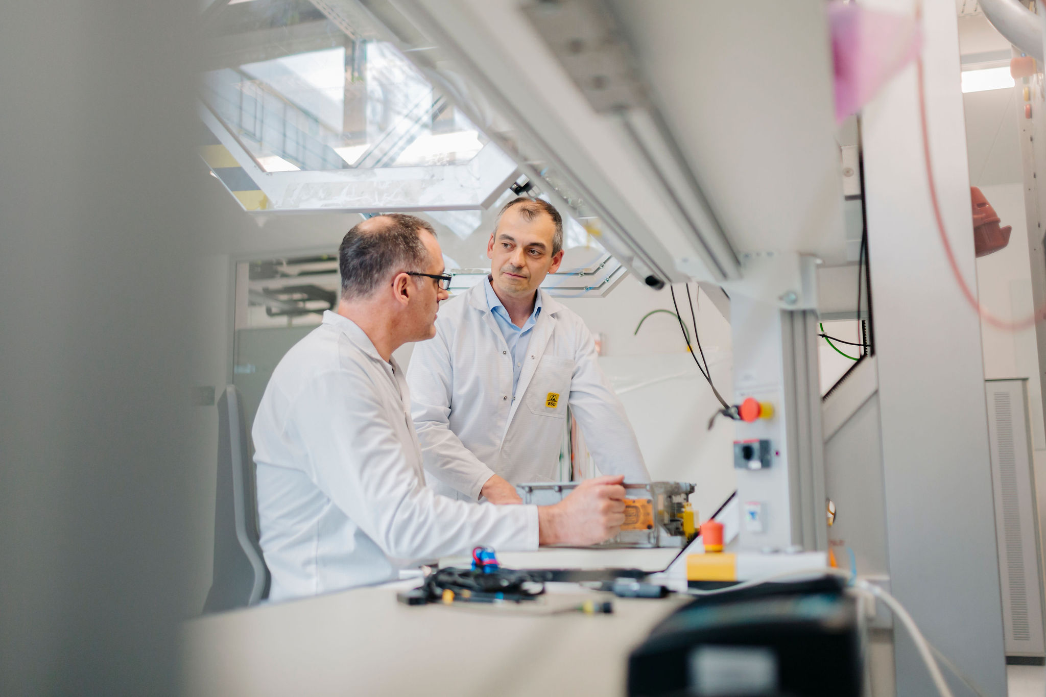 Two engineers discussing a technical setup at a laboratory workstation with electronic components
