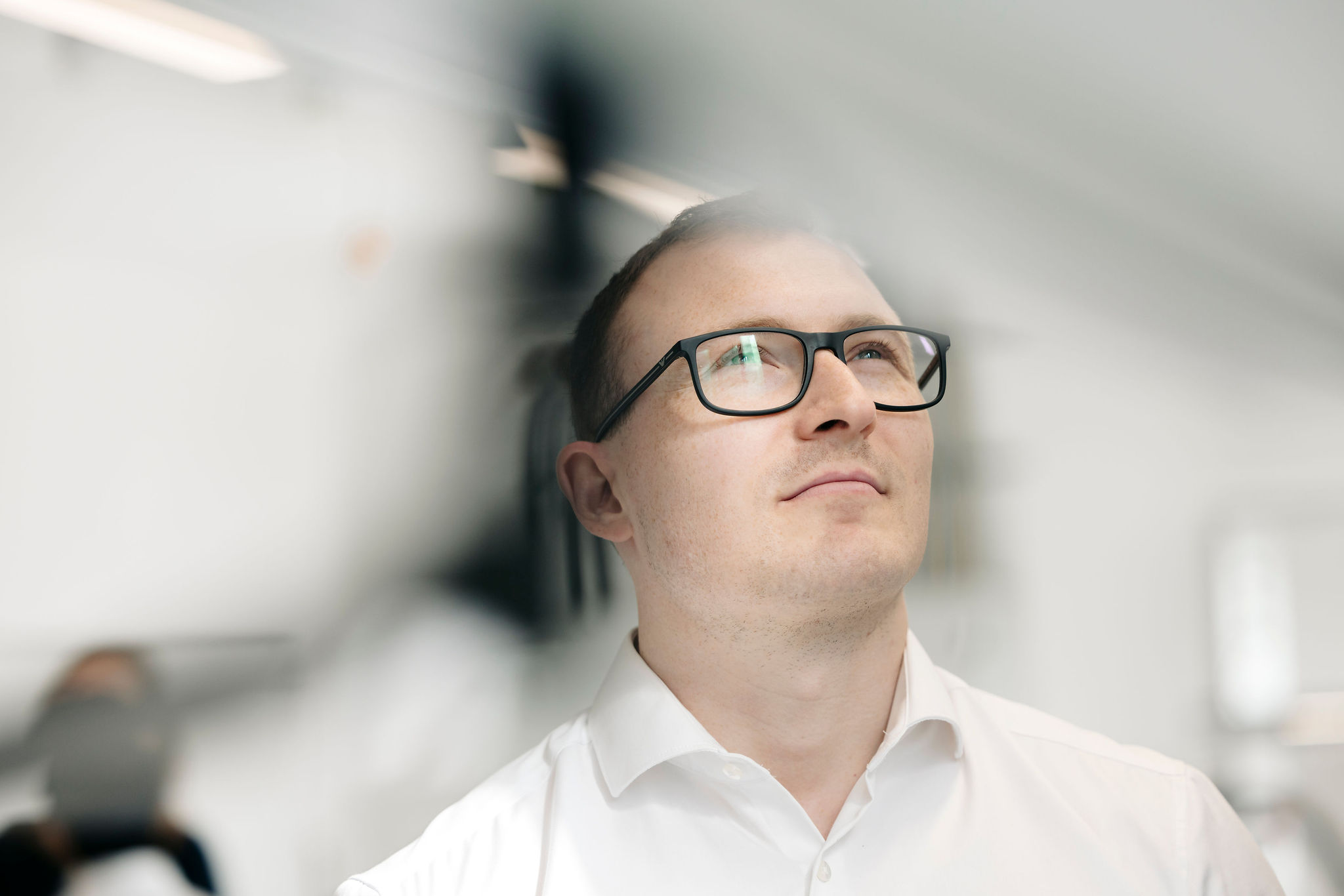 Silver Atena employee wearing glasses and a white shirt, focusing intently on technical equipment in the development laboratory.