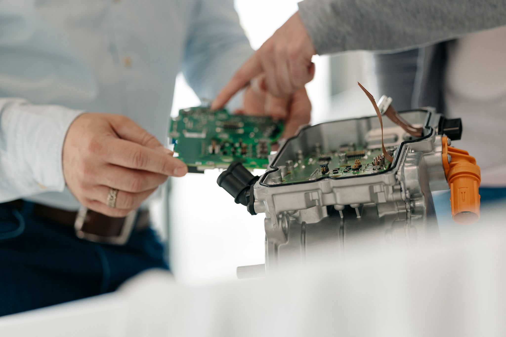Two Silver Atena engineers examining an electronic circuit board and its integration into a control unit housing.
