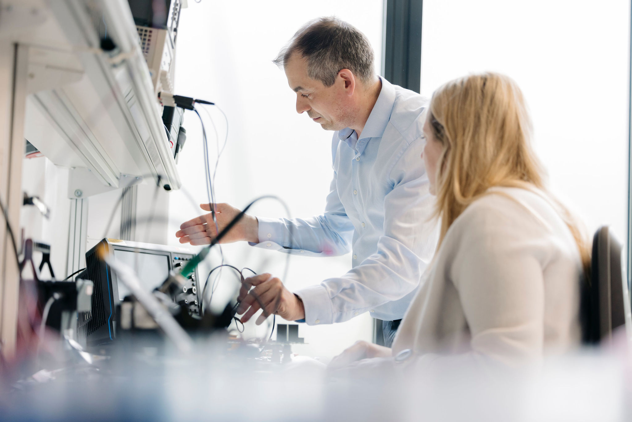 Two Silver Atena employees discussing measurements at an electronic test setup in the development laboratory.