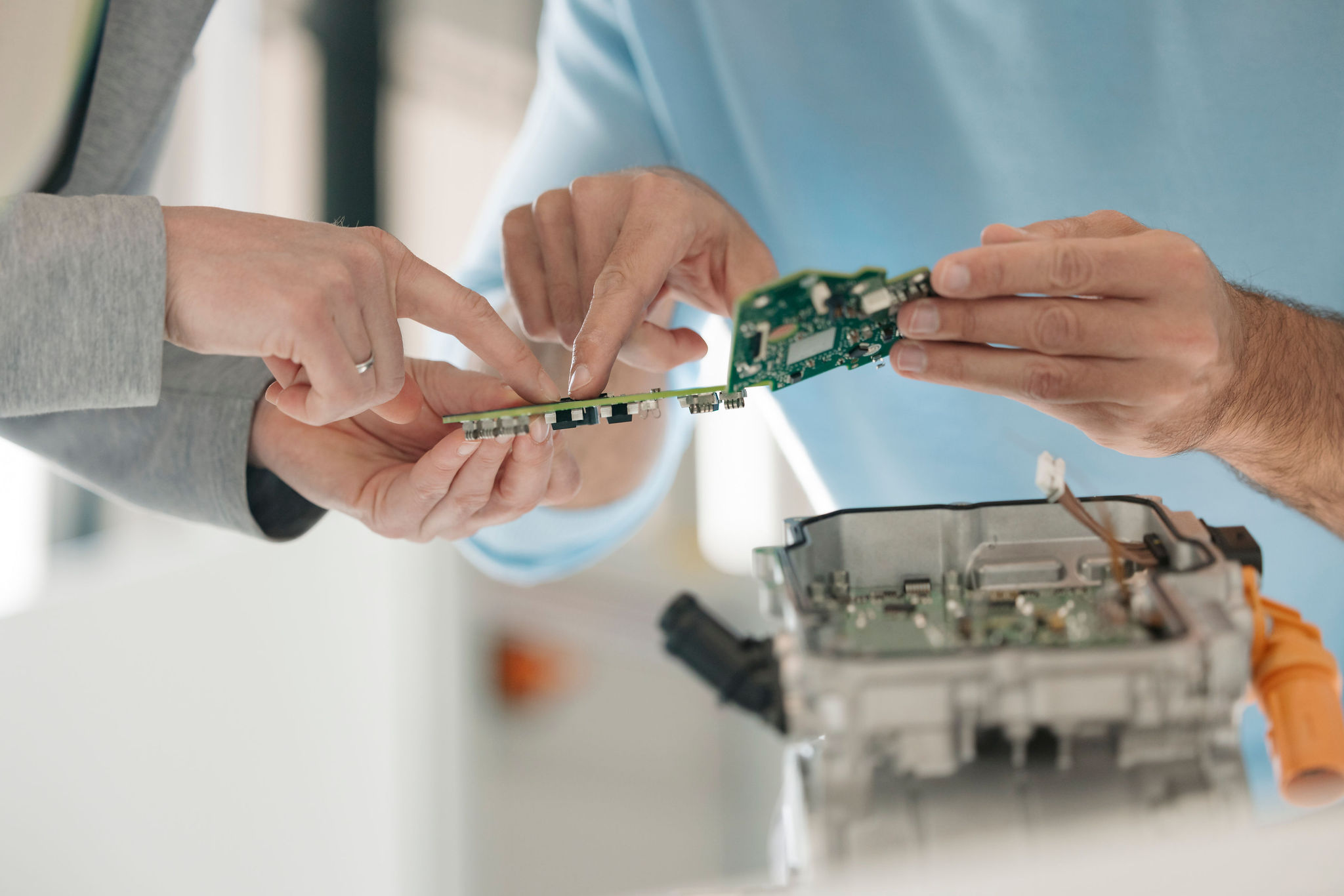Two Silver Atena employees discussing printed circuit boards (PCBs) and their integration into an open control unit housing.