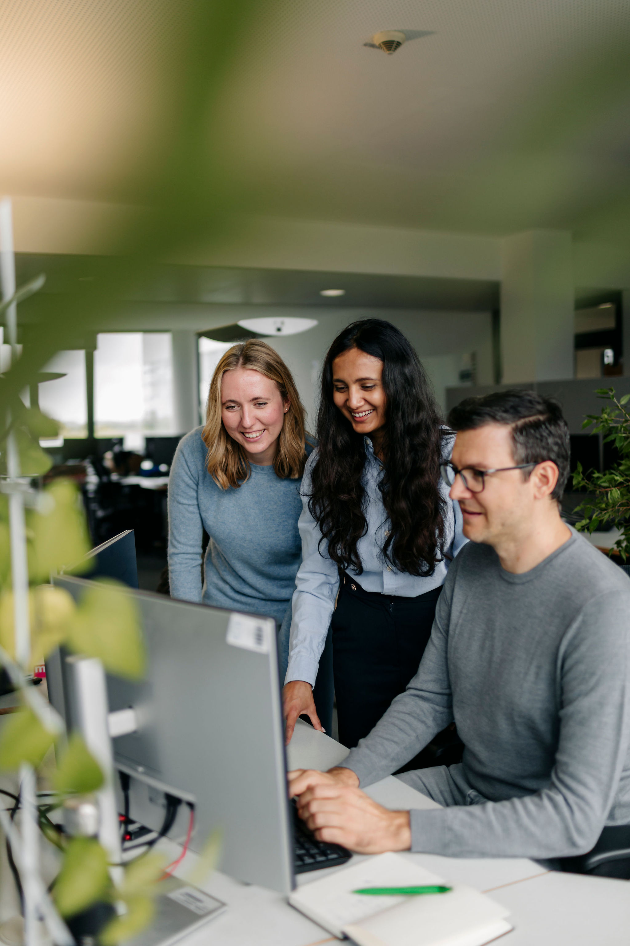 Three Silver Atena employees working together at a computer workstation and discussing technical project details.