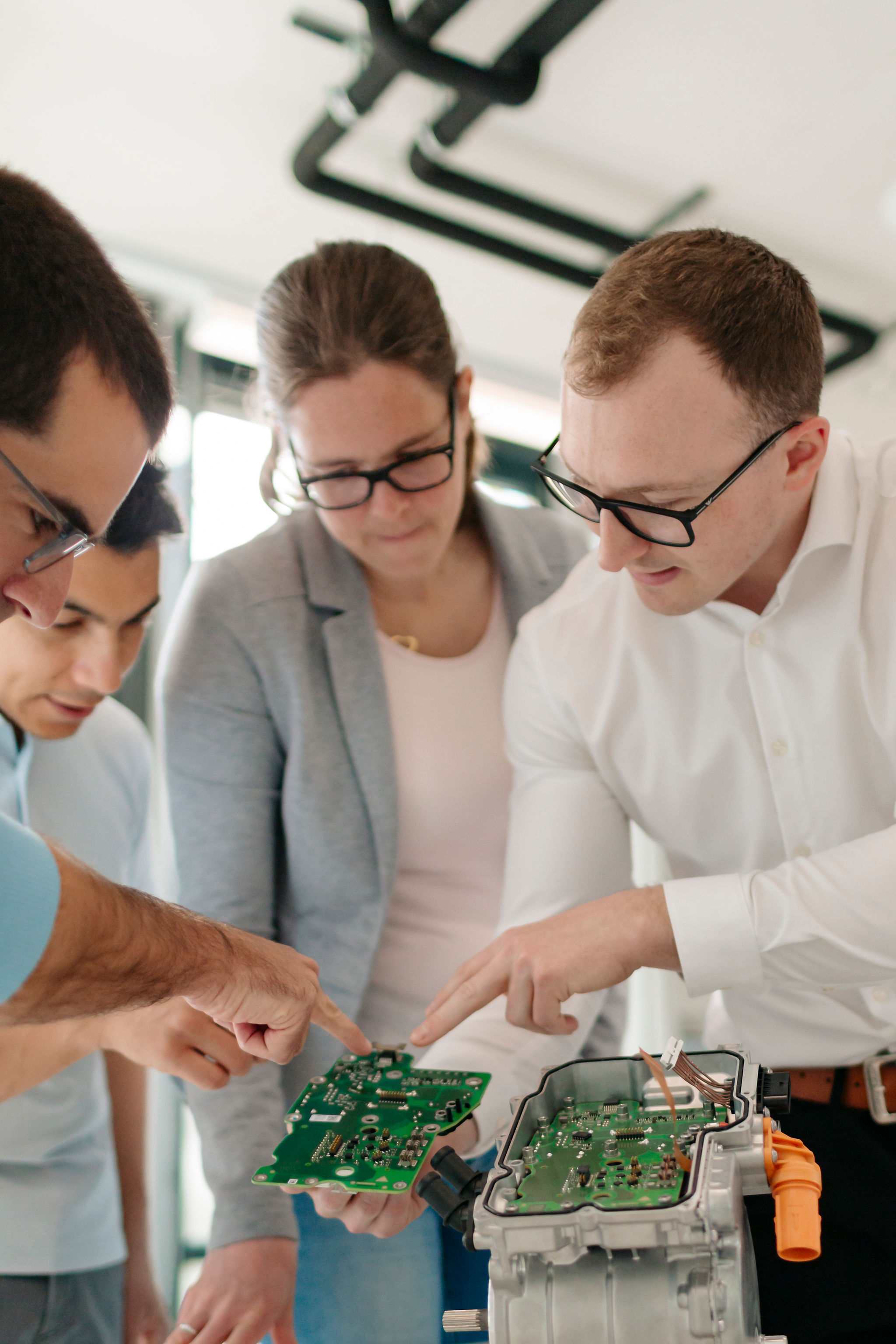 Four Silver Atena employees examining printed circuit boards (PCBs) and their integration into an open control unit housing.