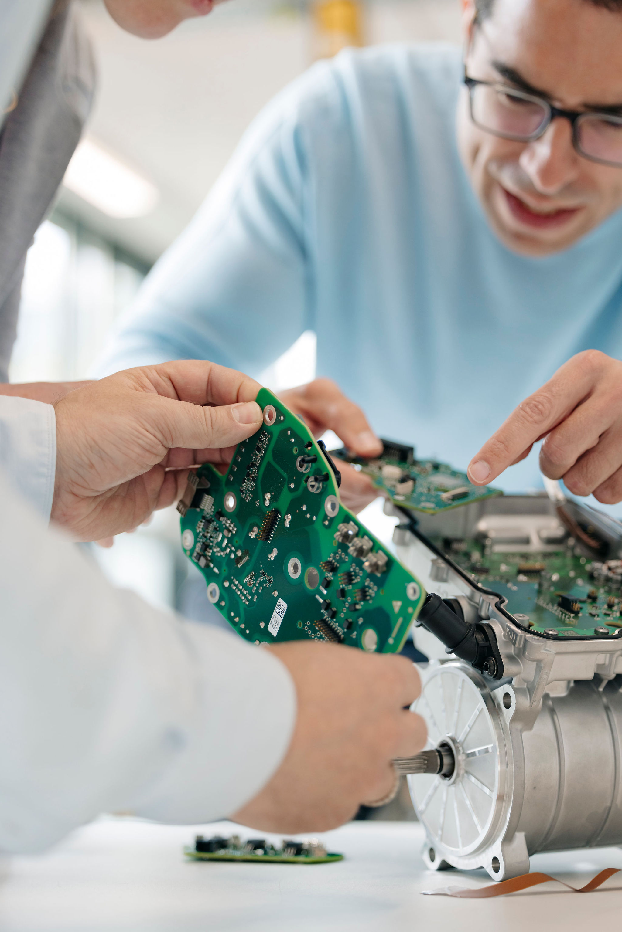 Two Silver Atena engineers comparing printed circuit boards with an opened drive unit in the development laboratory.