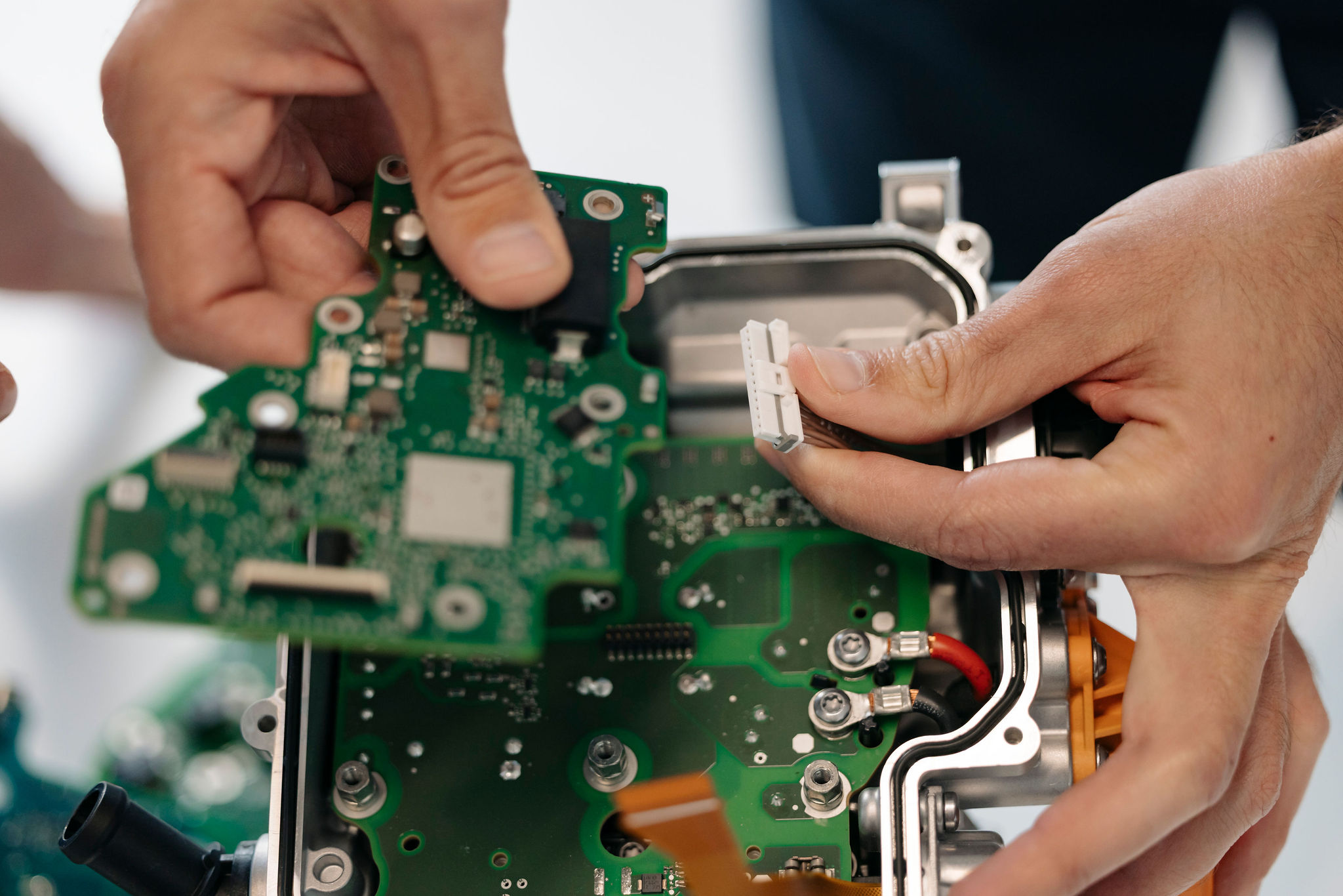 Close-up of an assembled printed circuit board (PCB) and a connector during the assembly of an electronic control unit.