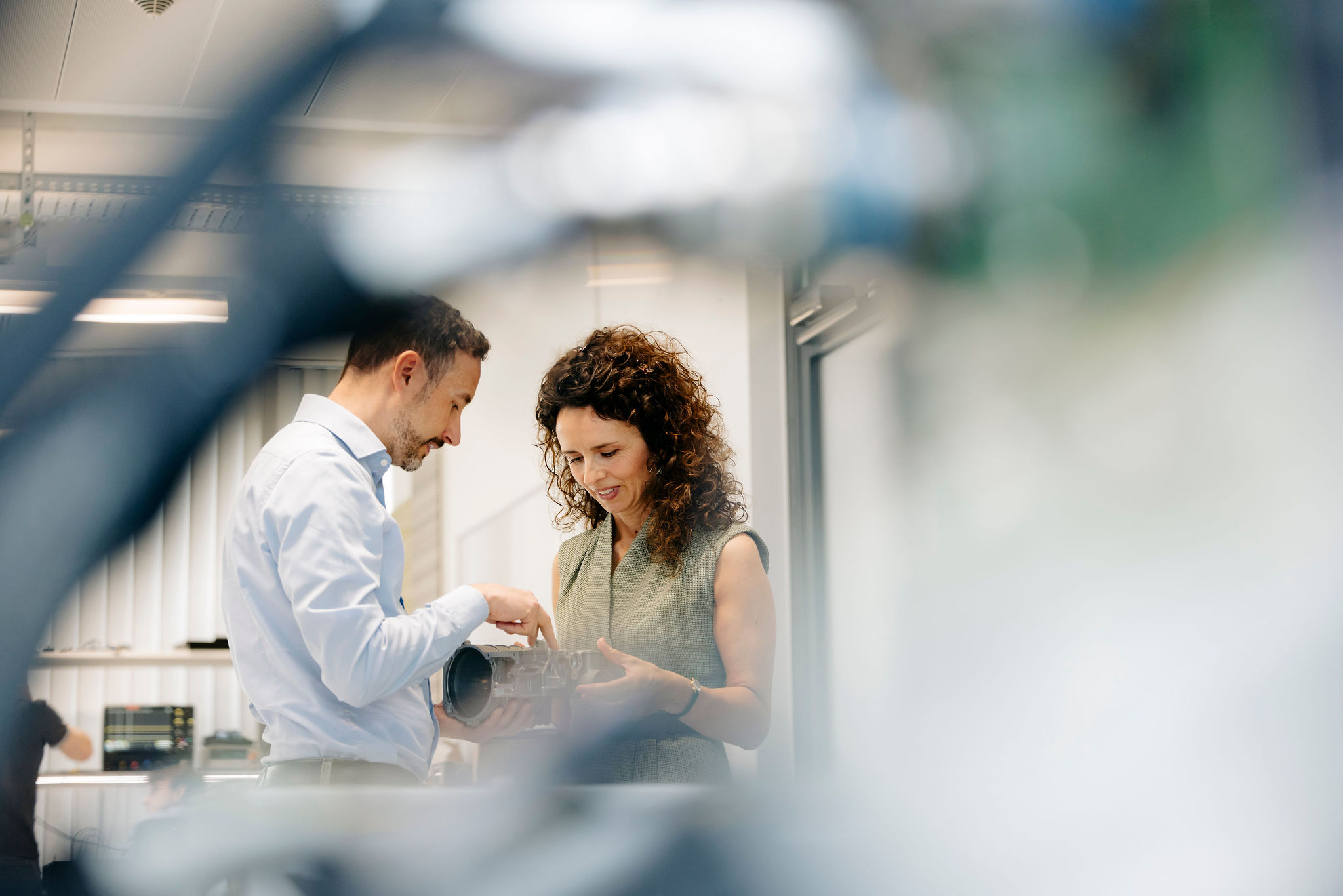 Two Silver Atena employees discussing the mechanical design and technical construction of a metal drive housing.