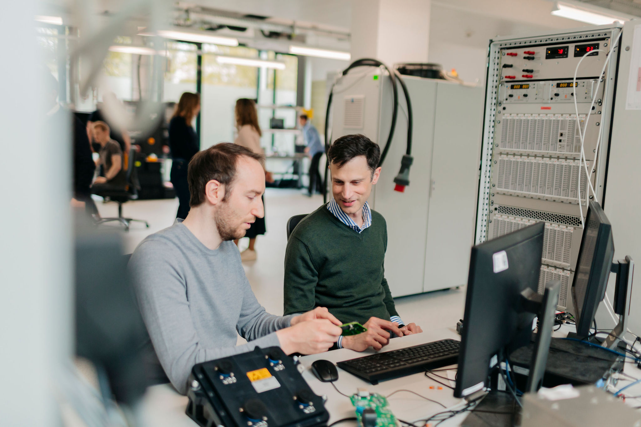 Two Silver Atena engineers discussing the system integration of an electronic assembly at a computer workstation.
