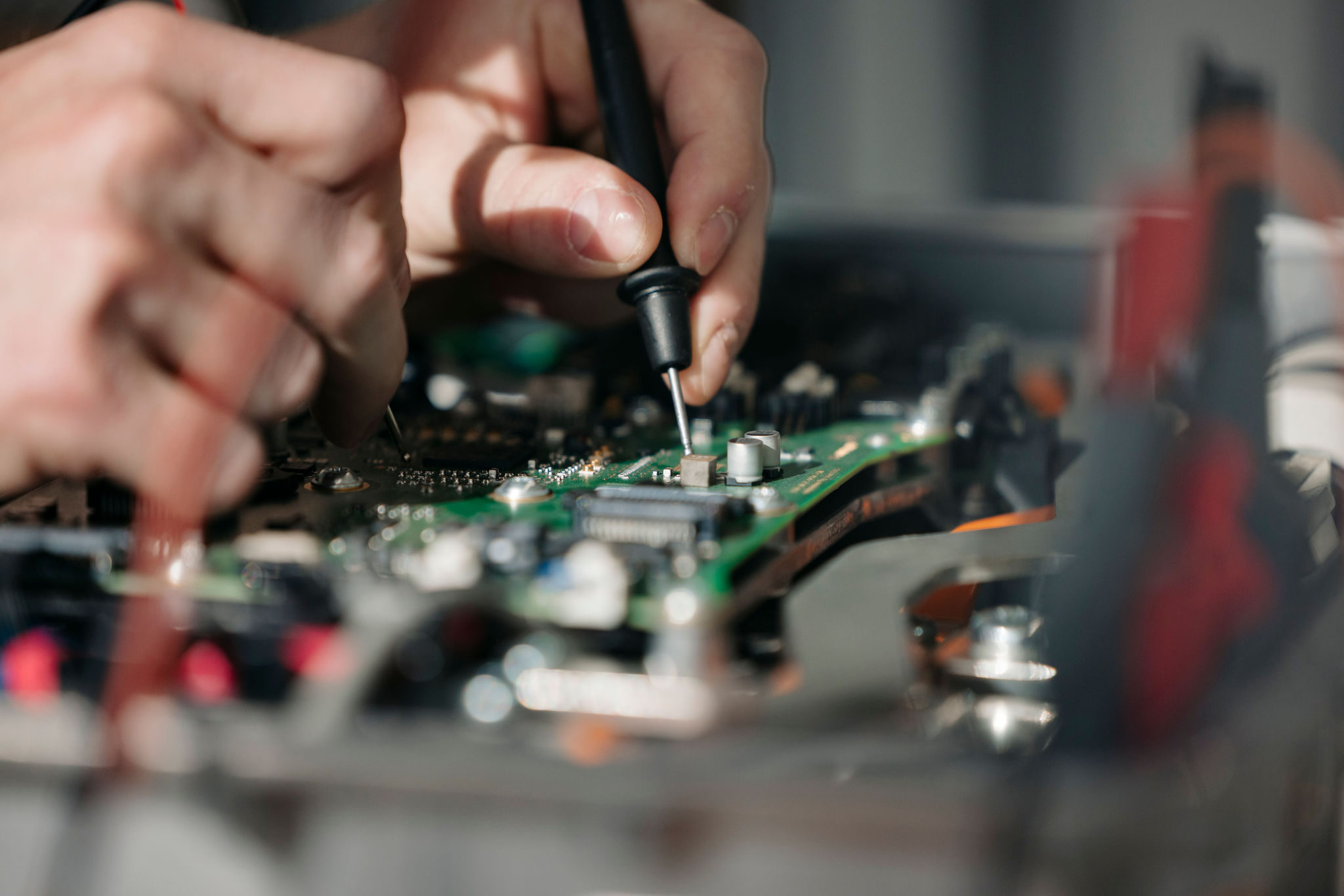 Close-up of a printed circuit board (PCB) being tested with a measurement probe touching an electronic component.