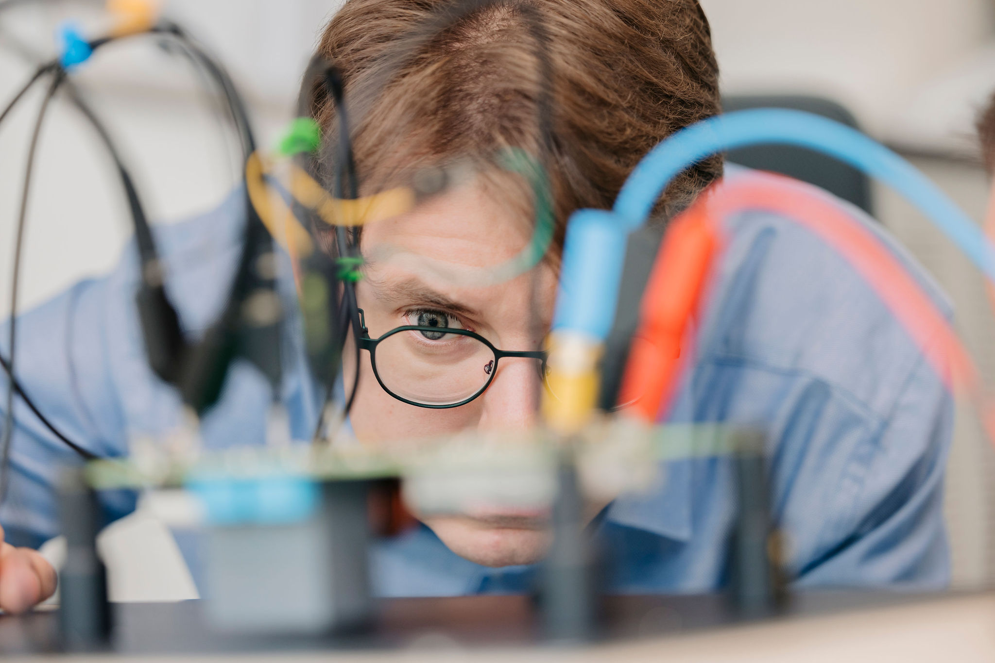 Silver Atena engineer closely inspecting a printed circuit board (PCB) with connected measurement cables.
