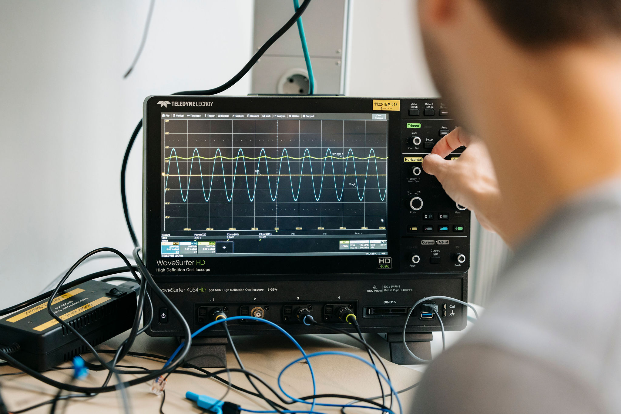 Engineer analyzing electrical signals on an oscilloscope during power electronics development and testing.