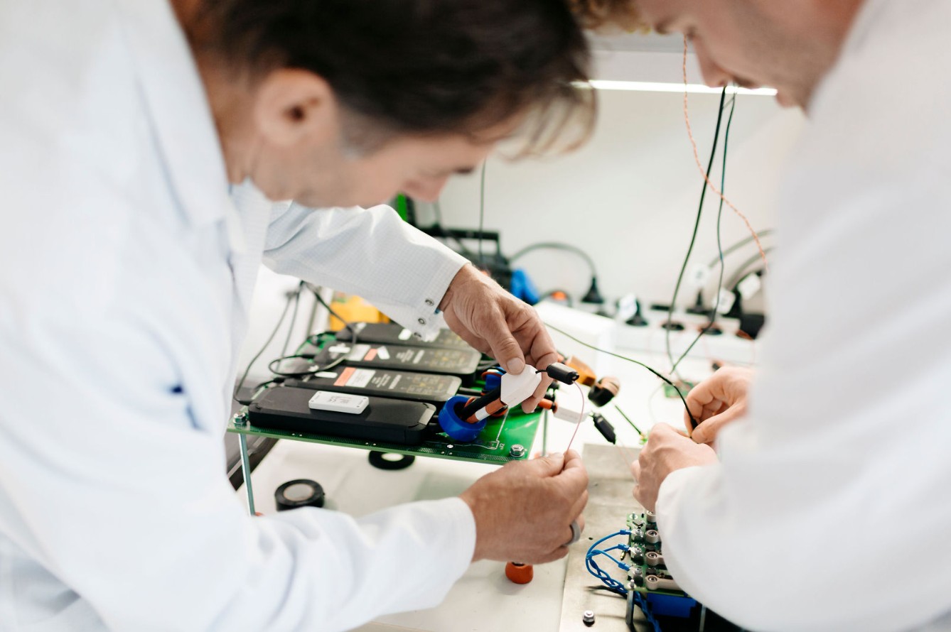 Silver Atena engineers connecting electronic components during a laboratory system test.