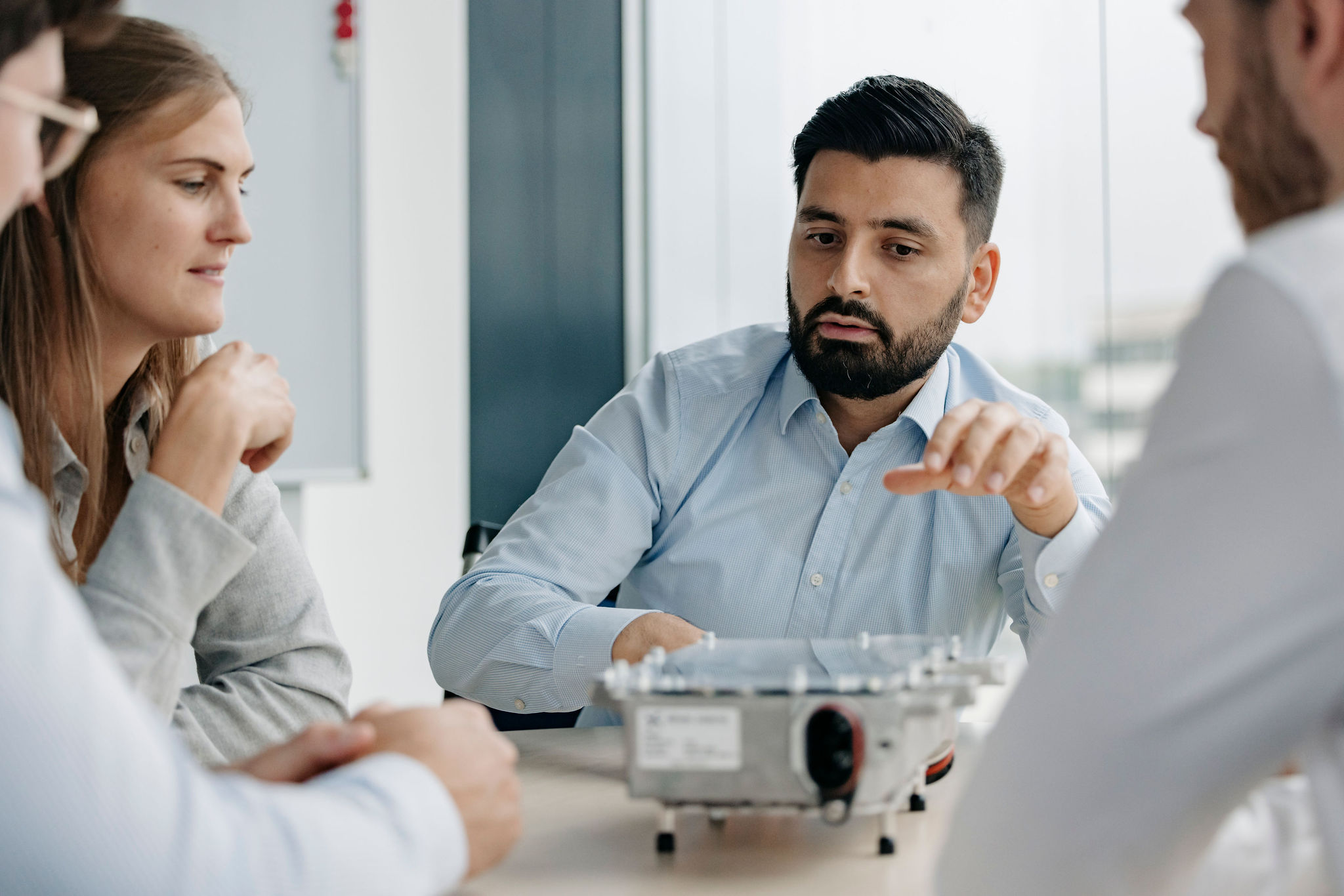 Group in a meeting with an electronic unit placed on the table.